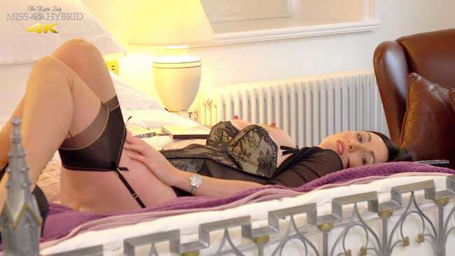 Miss Hybrid suspender twanging in seamed stockings on the bed.